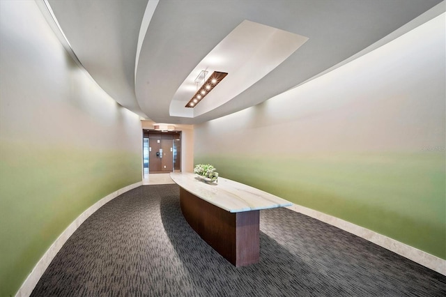 hallway with a tray ceiling and carpet flooring