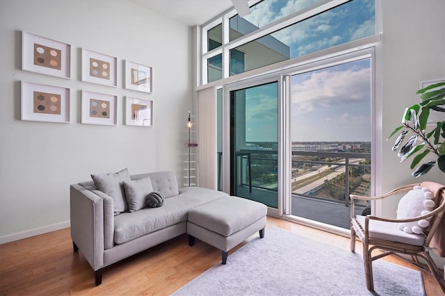 living room with a towering ceiling, wood-type flooring, and expansive windows