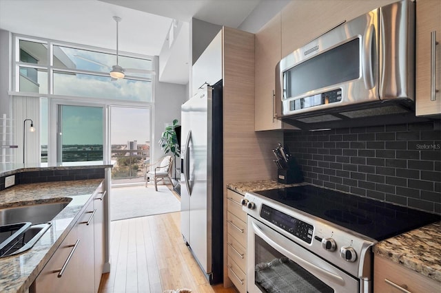 kitchen with light stone counters, pendant lighting, decorative backsplash, and appliances with stainless steel finishes