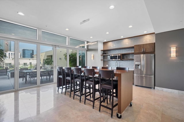 kitchen featuring tasteful backsplash, a kitchen breakfast bar, a center island, dark brown cabinetry, and stainless steel refrigerator with ice dispenser