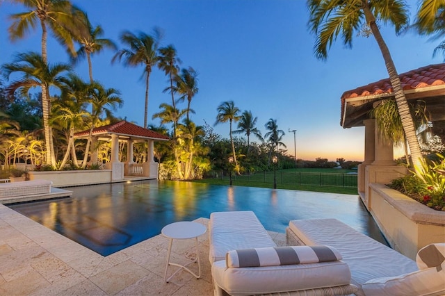 pool at dusk featuring a gazebo