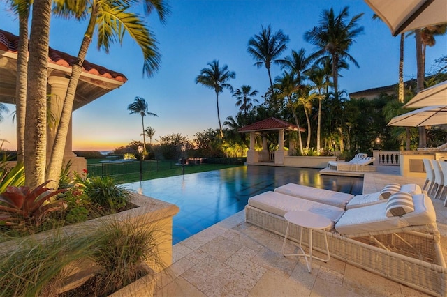 pool at dusk featuring a patio area