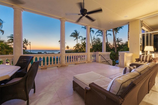 patio terrace at dusk with a water view, an outdoor hangout area, and ceiling fan