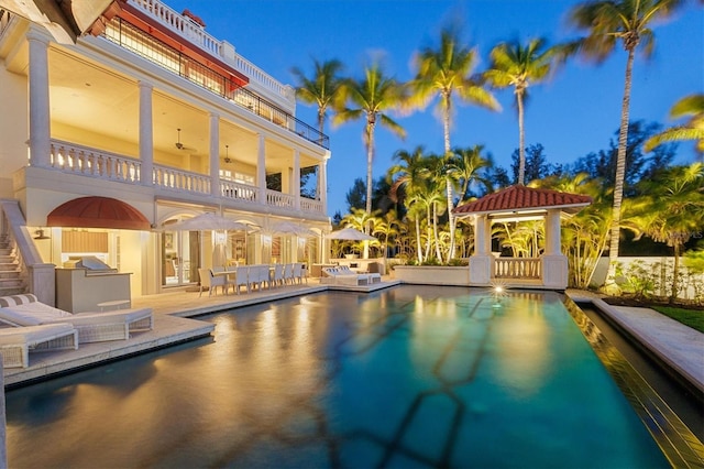 view of pool with ceiling fan, a gazebo, exterior bar, a patio area, and exterior kitchen