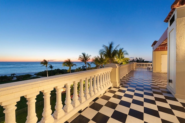 balcony at dusk featuring a water view