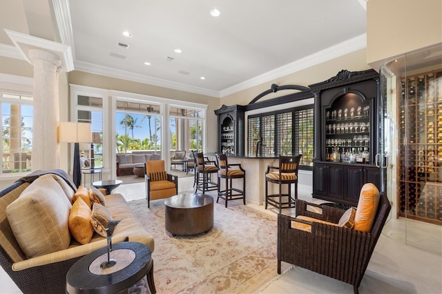 interior space with decorative columns, crown molding, light tile patterned flooring, and bar area