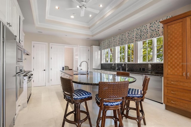 kitchen with white cabinetry, dishwasher, sink, dark stone counters, and a tray ceiling