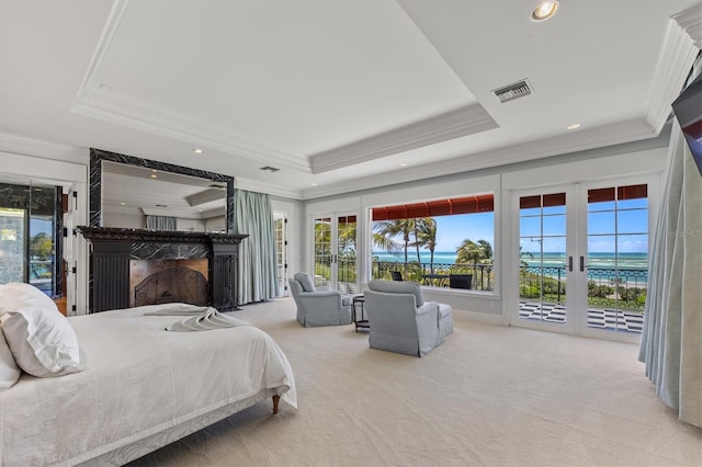 bedroom featuring french doors, a water view, a tray ceiling, and access to outside