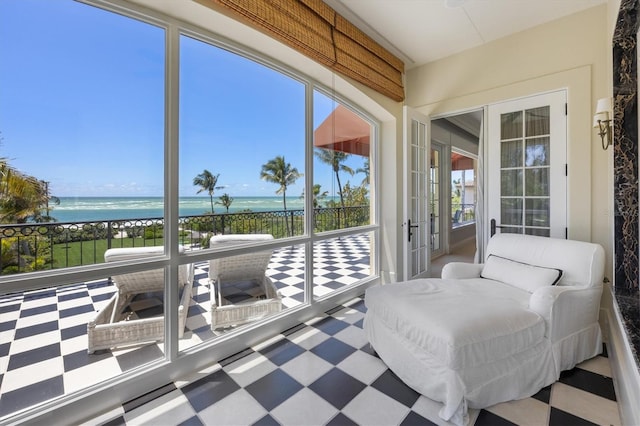 sunroom / solarium featuring a water view and a beach view