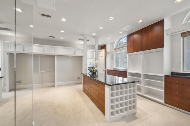 spacious closet with ornate columns and light carpet