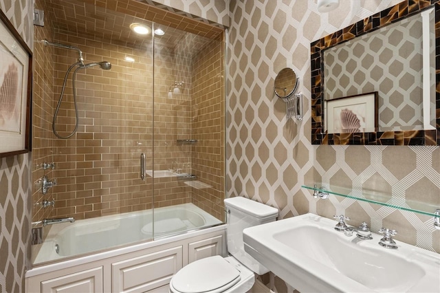 full bathroom featuring toilet, bath / shower combo with glass door, and sink