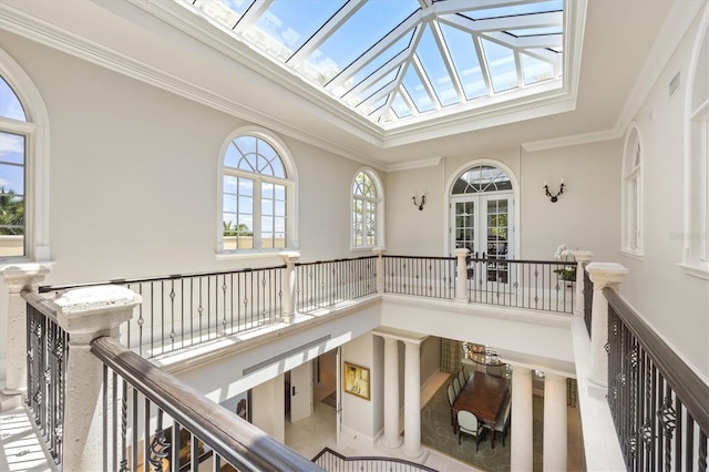 hallway with french doors, ornamental molding, a towering ceiling, and a skylight