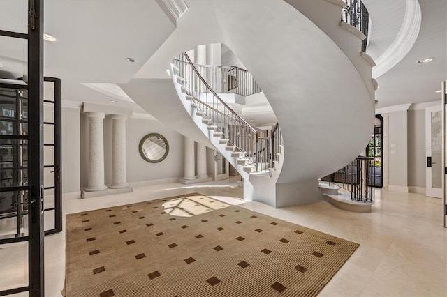 foyer entrance with ornate columns, ornamental molding, and a towering ceiling