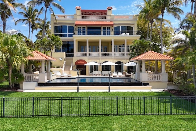 rear view of property featuring a balcony, a lawn, a fenced in pool, a gazebo, and a patio area