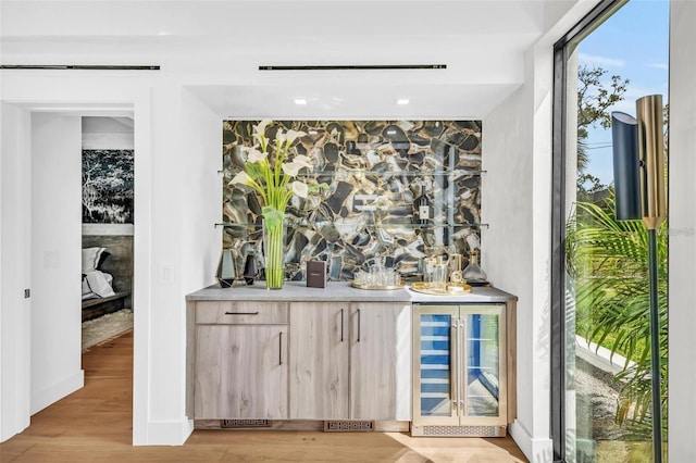 bar featuring wine cooler, light brown cabinetry, and light hardwood / wood-style floors