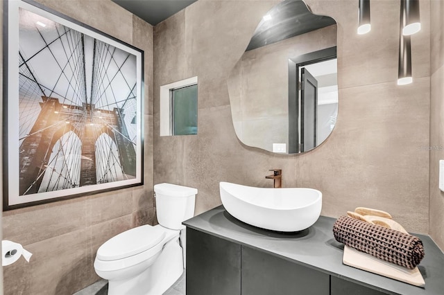 bathroom with vanity, tile walls, and toilet