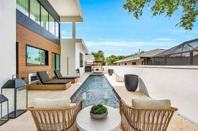 view of pool with a patio, pool water feature, and glass enclosure