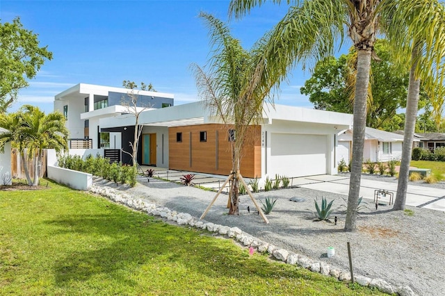 contemporary house with driveway, an attached garage, fence, a front lawn, and stucco siding