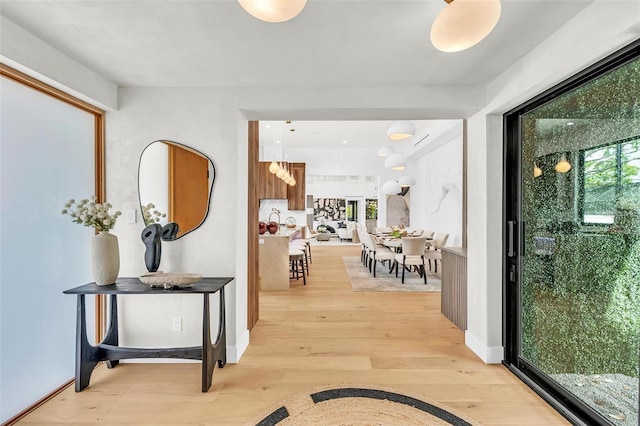 hall with light wood-style flooring and baseboards