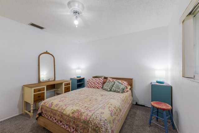 bedroom with a textured ceiling and dark carpet