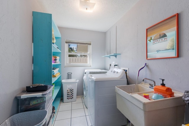 clothes washing area with laundry area, a textured wall, tile patterned floors, a textured ceiling, and separate washer and dryer