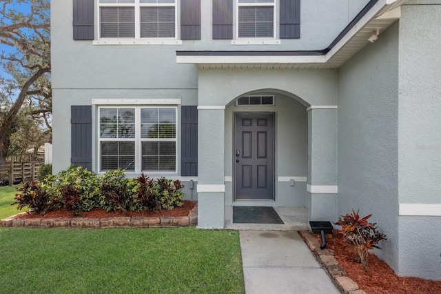 property entrance with a lawn