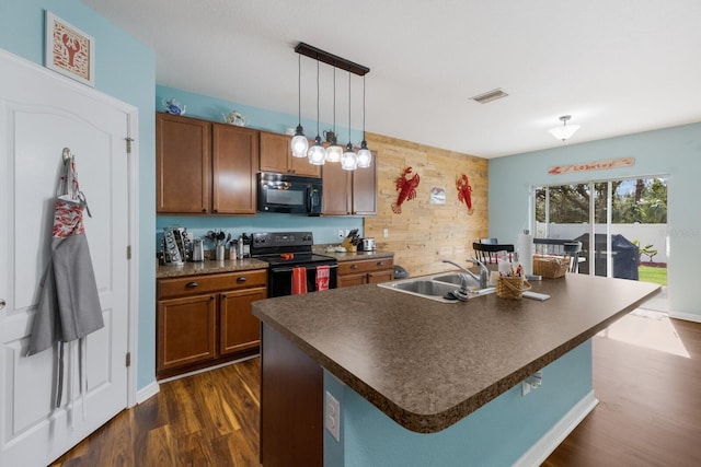 kitchen featuring pendant lighting, sink, dark hardwood / wood-style flooring, a kitchen island with sink, and black appliances