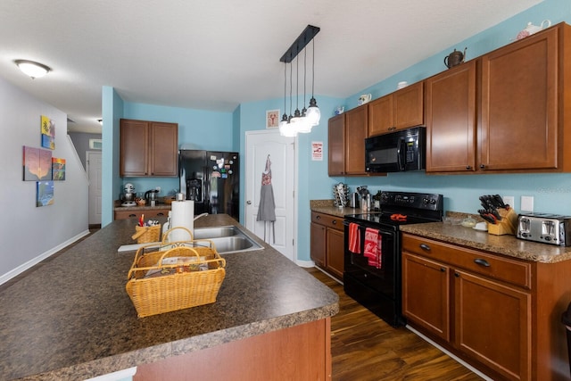 kitchen featuring a center island with sink, decorative light fixtures, dark wood-type flooring, and black appliances