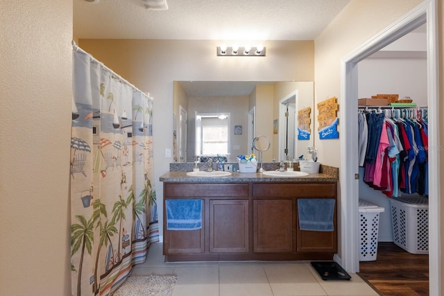 bathroom with a shower with curtain, tile patterned floors, vanity, and a textured ceiling