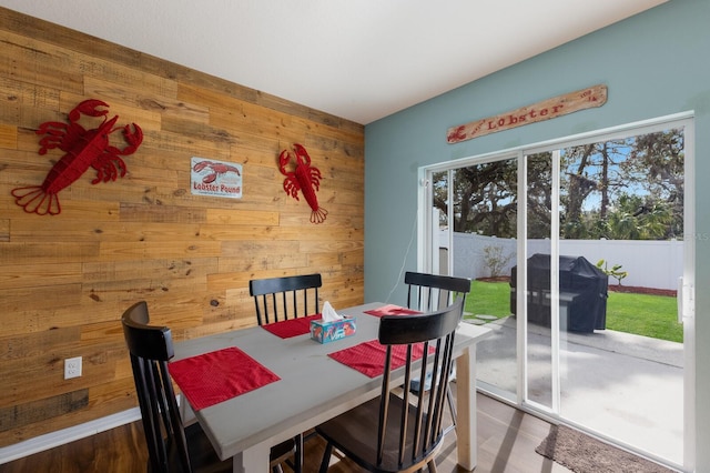 dining area featuring wooden walls and wood finished floors