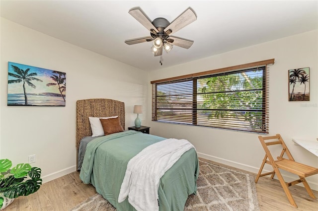 bedroom with multiple windows, wood-type flooring, and ceiling fan