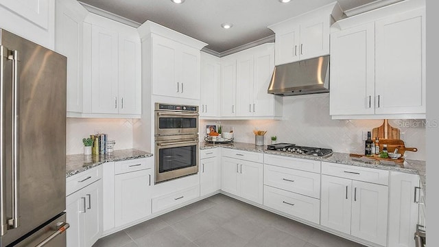 kitchen with light stone counters, tasteful backsplash, white cabinets, and appliances with stainless steel finishes