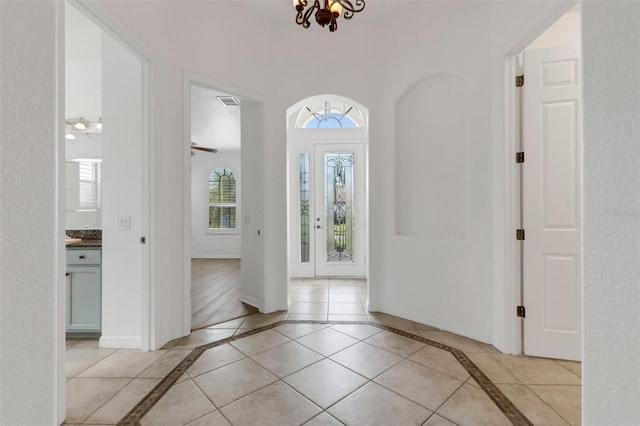 tiled foyer featuring a notable chandelier