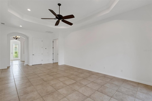 spare room with light tile patterned floors, a tray ceiling, and ceiling fan with notable chandelier