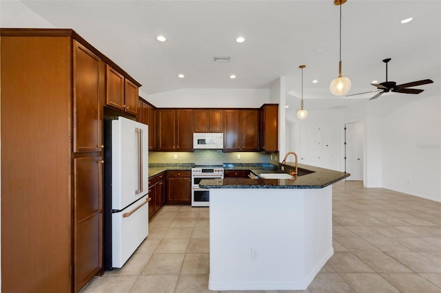 kitchen featuring pendant lighting, sink, white appliances, dark stone countertops, and tasteful backsplash