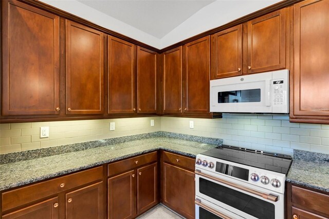 kitchen featuring stone counters, tasteful backsplash, and white appliances