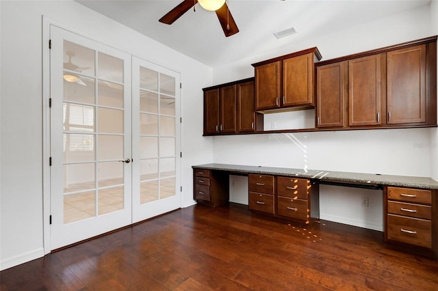 unfurnished office with ceiling fan, built in desk, dark hardwood / wood-style flooring, and french doors