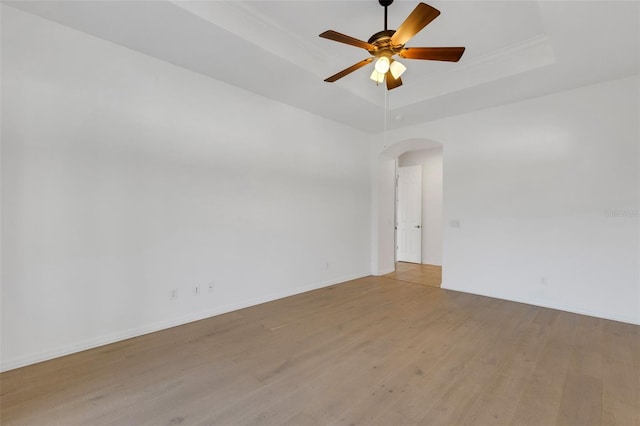 spare room with light hardwood / wood-style flooring, ceiling fan, and a tray ceiling