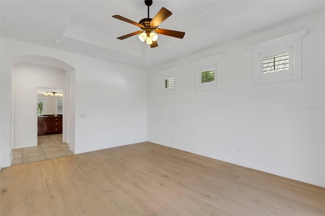 unfurnished room featuring ceiling fan, light hardwood / wood-style floors, and a tray ceiling