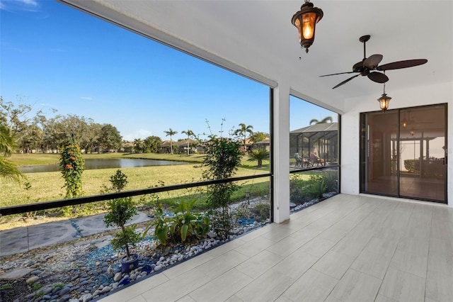 unfurnished sunroom featuring a water view and ceiling fan