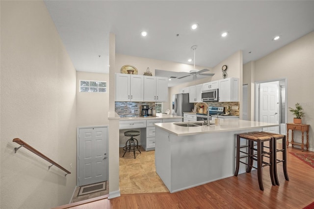 kitchen with stainless steel appliances, white cabinetry, an island with sink, and a kitchen breakfast bar