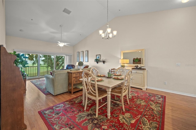 dining area featuring ceiling fan with notable chandelier, light hardwood / wood-style flooring, and high vaulted ceiling