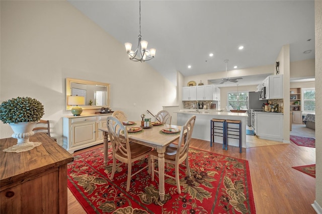 dining room featuring high vaulted ceiling, a chandelier, and light wood-type flooring