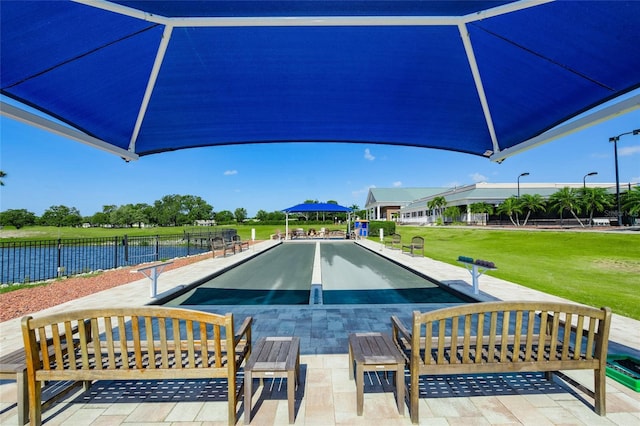 view of swimming pool with a water view and a lawn