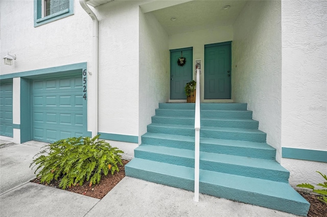 entrance to property featuring a garage and stucco siding