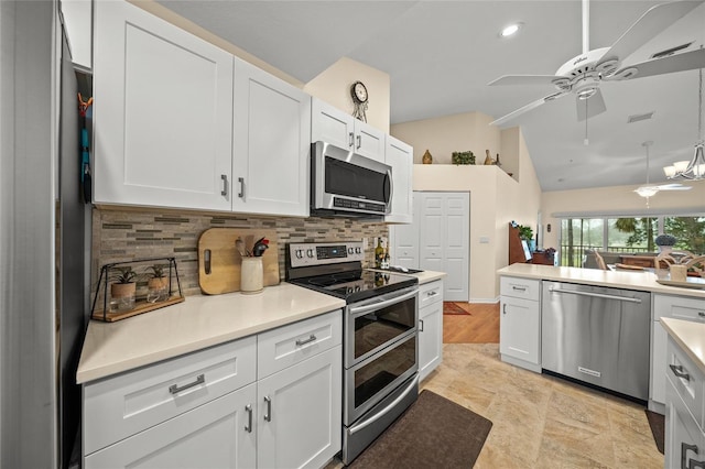 kitchen with stainless steel appliances, white cabinets, light countertops, and vaulted ceiling