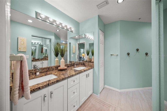 full bath with double vanity, a closet, visible vents, and a sink