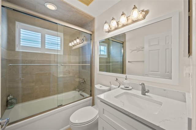 full bath with shower / bath combination with glass door, vanity, toilet, and a healthy amount of sunlight