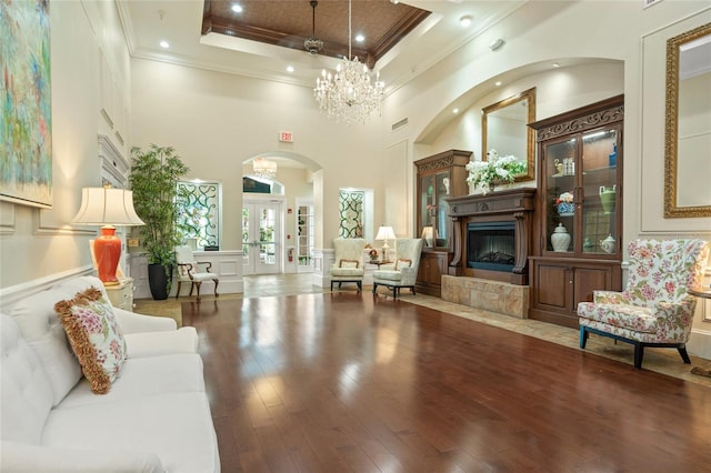 interior space with arched walkways, crown molding, wood finished floors, a chandelier, and a tile fireplace