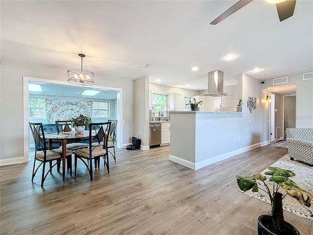 dining area featuring ceiling fan with notable chandelier, sink, and light hardwood / wood-style floors